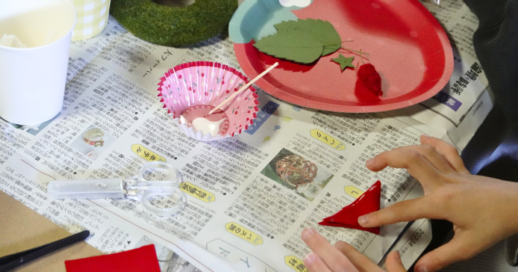 【ワークショップ実施報告】2025年11月23日（日）こびとの農園×PlusOneSchool「イチゴの小さなクリスマスリース」布を折っている子ども