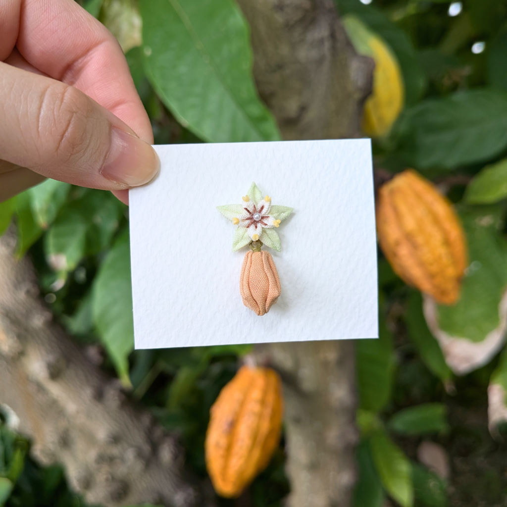 つまみ細工「カカオのピンバッジ」本物のカカオ（成熟実）との写真